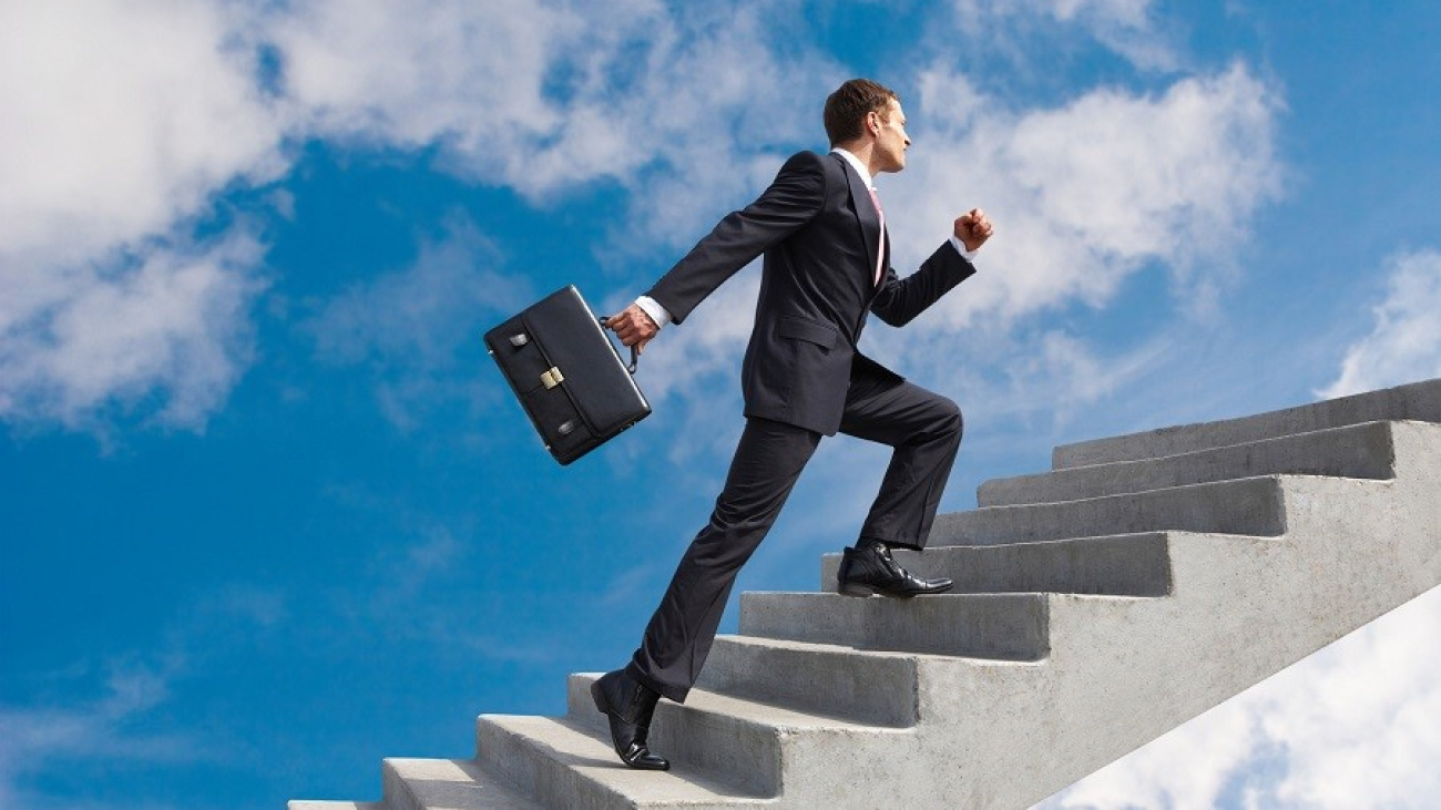 Image of confident businessman with briefcase walking upstairs